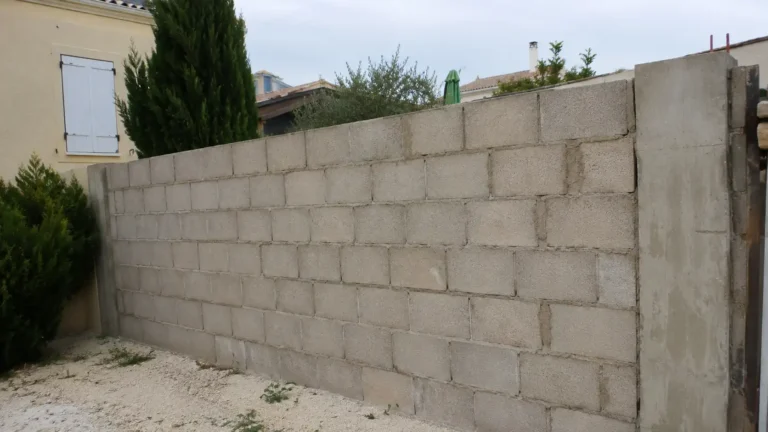 Mur extérieur en parpaing brut laissé sans enduit entre deux propriétés