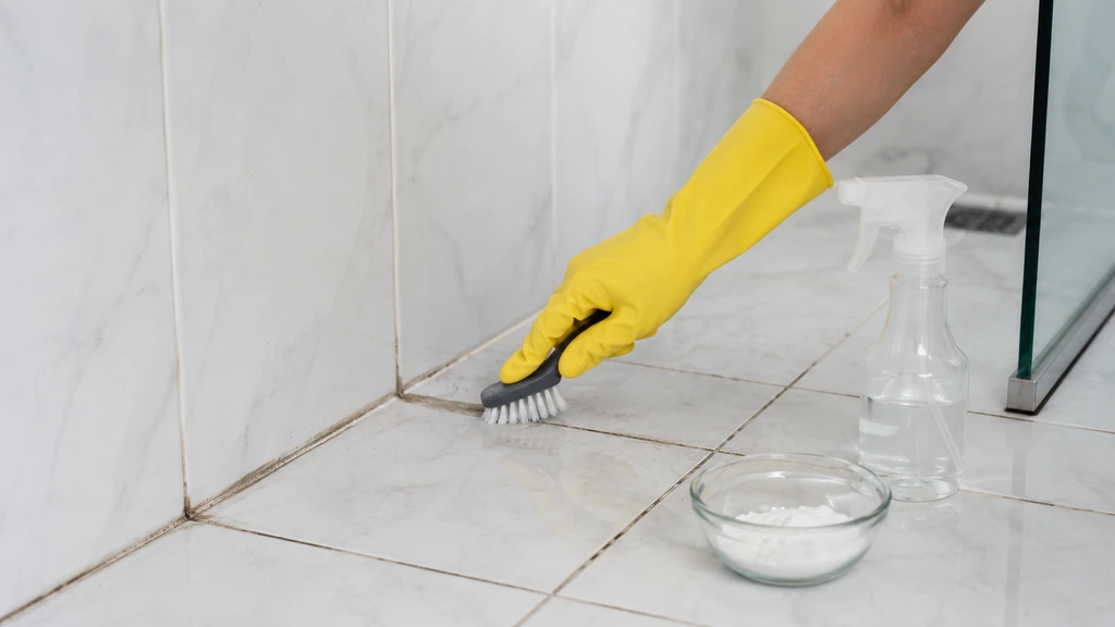 Nettoyage des joints de salle de bain avec une brosse et du bicarbonate